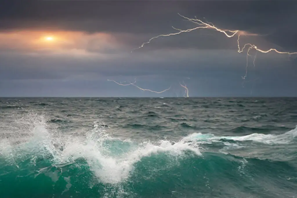 Stormy ocean waves with lightning in the distance, symbolizing the journey through uncertainty and transformation.