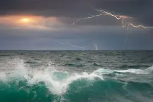 Stormy ocean waves with lightning in the distance, symbolizing the journey through uncertainty and transformation.